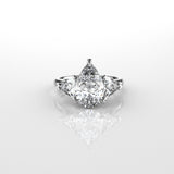 Pear shaped centre with trillion side diamonds ring with a star-shaped prong setting on a white background