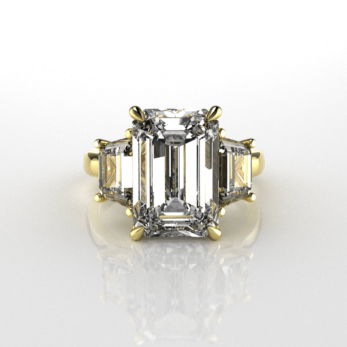Diamond ring with emerald-cut stones on a white background in yellow gold