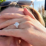 Close-up of a person wearing sunglasses with a large pear cut 3 stone diamond ring on their finger